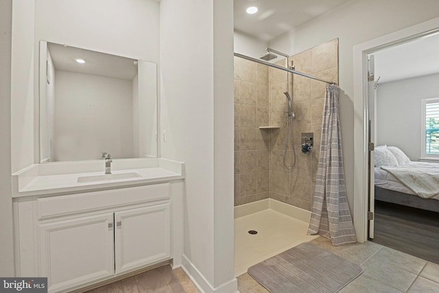 bathroom with connected bathroom, a tile shower, vanity, and tile patterned floors