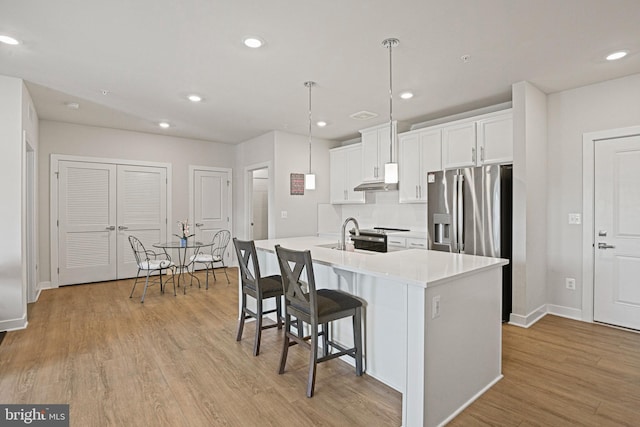 kitchen with light countertops, light wood-type flooring, a kitchen bar, and white cabinets