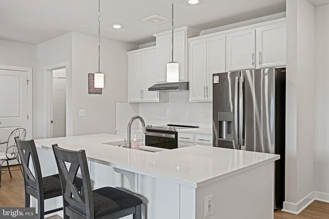 kitchen featuring extractor fan, white cabinetry, light wood-style floors, appliances with stainless steel finishes, and decorative backsplash