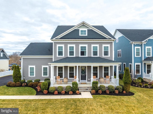 view of front of house featuring a porch, a front yard, and a shingled roof