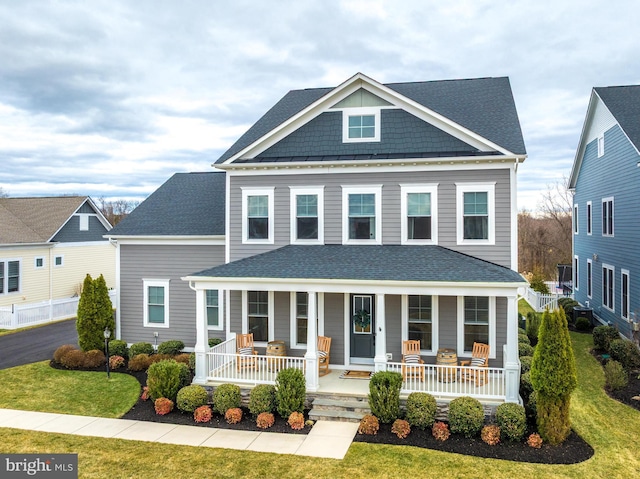 view of front of home with a front yard, a porch, and roof with shingles