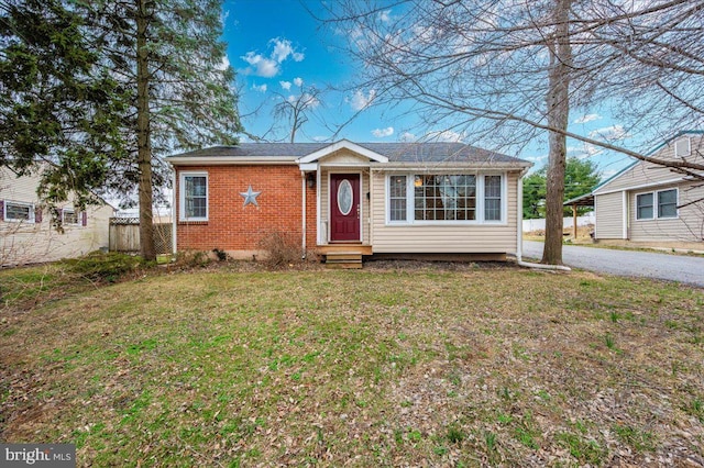 view of front of property featuring entry steps, a front lawn, fence, and brick siding