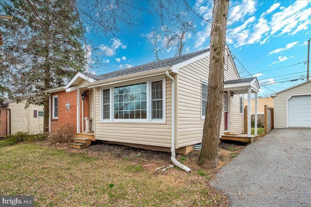 view of front of house featuring an outdoor structure, a garage, driveway, and a front lawn