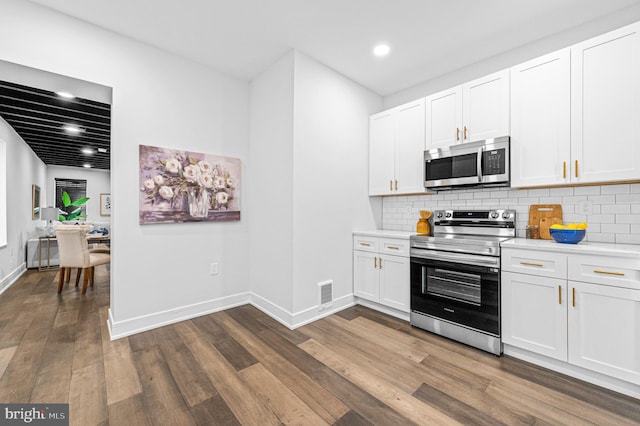 kitchen with visible vents, decorative backsplash, dark wood-type flooring, stainless steel appliances, and light countertops