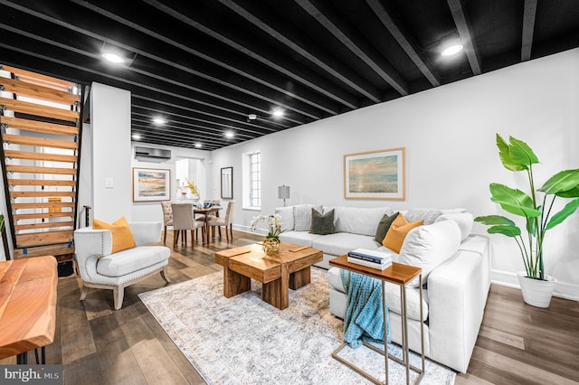 living area featuring baseboards, beam ceiling, and wood finished floors