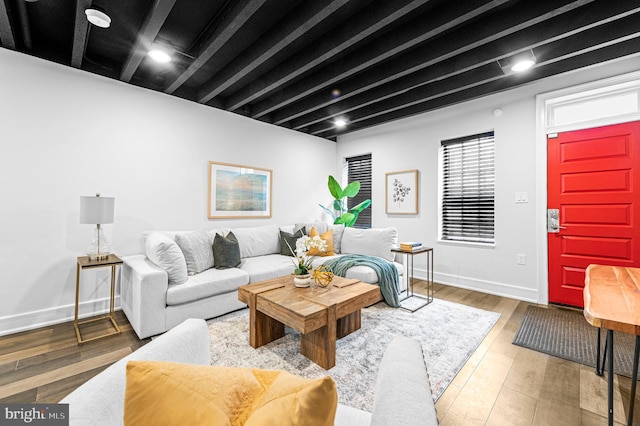 living room featuring baseboards, beam ceiling, and wood finished floors