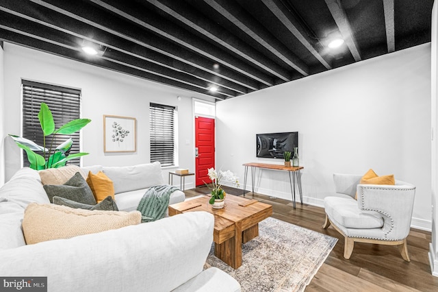 living area with beamed ceiling, baseboards, and wood finished floors