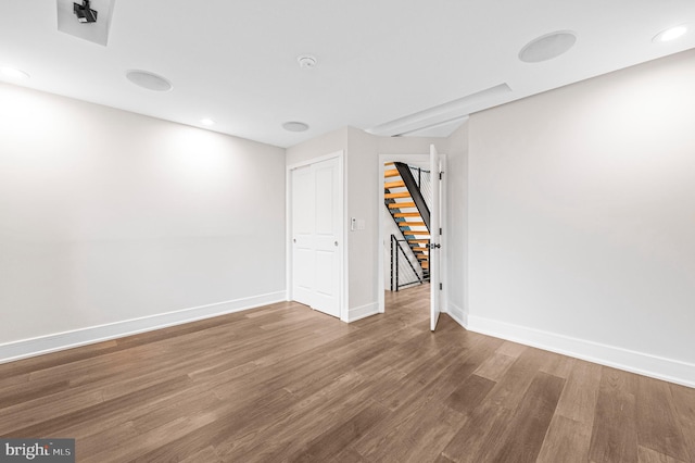 empty room featuring stairs, recessed lighting, wood finished floors, and baseboards