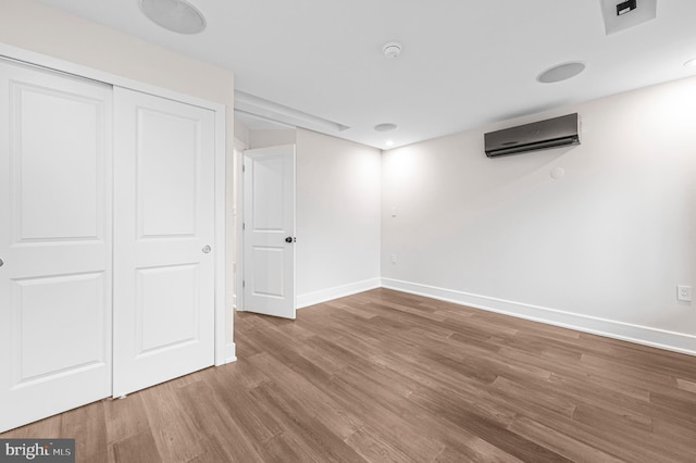 basement with a wall unit AC, baseboards, and wood finished floors