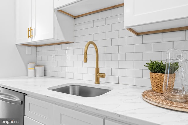 kitchen with dishwasher, backsplash, white cabinets, and a sink