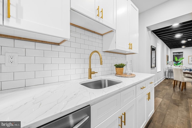 kitchen with stainless steel dishwasher, tasteful backsplash, white cabinetry, and a sink