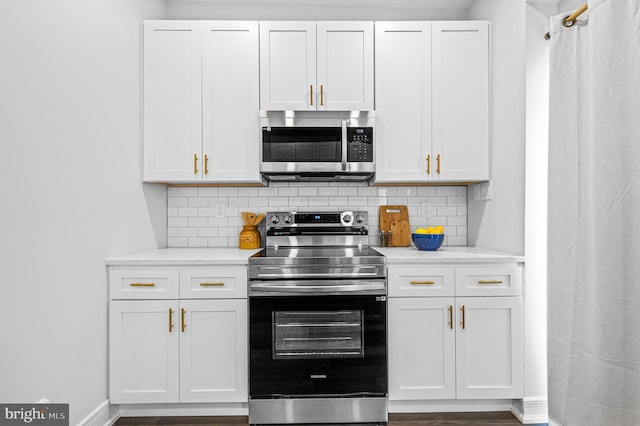 kitchen featuring stainless steel appliances, white cabinetry, backsplash, and baseboards