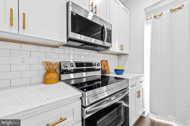 kitchen featuring stainless steel appliances, white cabinets, light stone counters, and tasteful backsplash