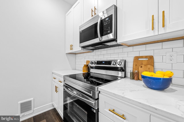 kitchen with white cabinets, light stone countertops, visible vents, and stainless steel appliances