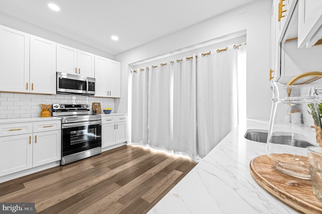 kitchen with stainless steel appliances, backsplash, dark wood-type flooring, white cabinetry, and a sink