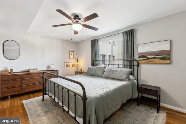 bedroom with a ceiling fan, baseboards, and wood finished floors