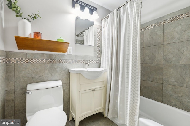 bathroom with toilet, shower / bath combo, tile walls, wainscoting, and vanity