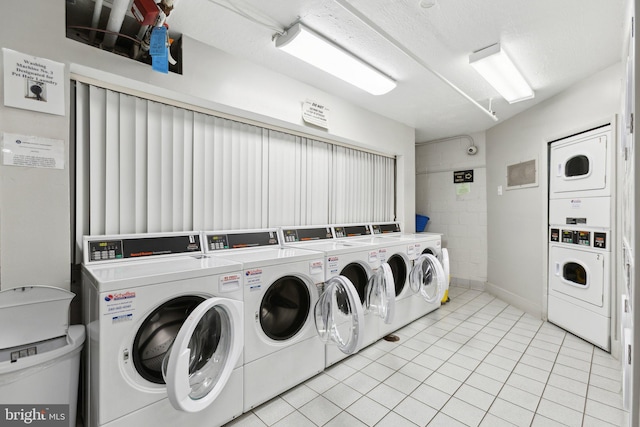 community laundry room with stacked washer / dryer, light tile patterned floors, and washing machine and dryer