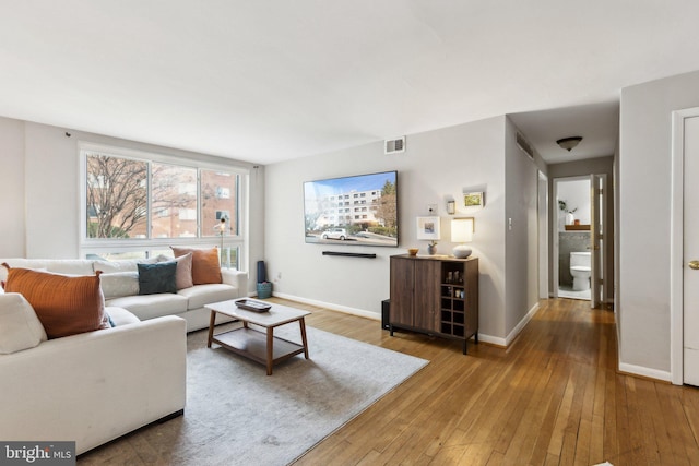 living area featuring hardwood / wood-style flooring, baseboards, and visible vents