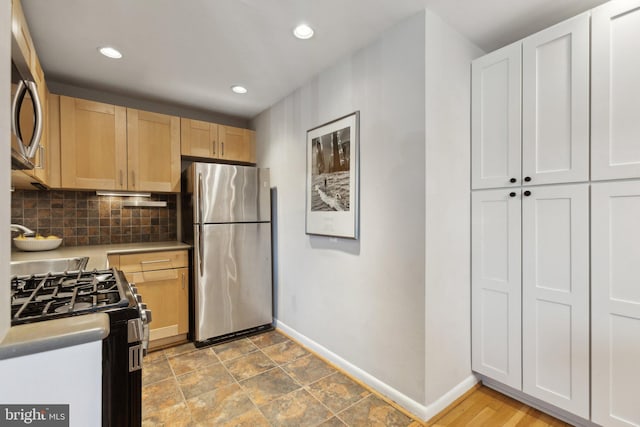 kitchen featuring light countertops, baseboards, backsplash, and stainless steel appliances