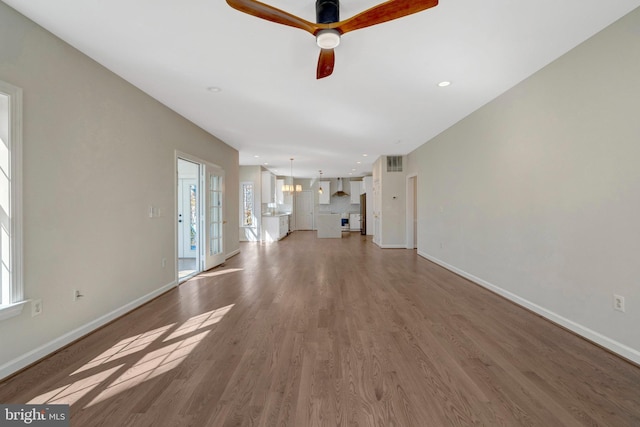 unfurnished living room with visible vents, baseboards, a ceiling fan, wood finished floors, and recessed lighting