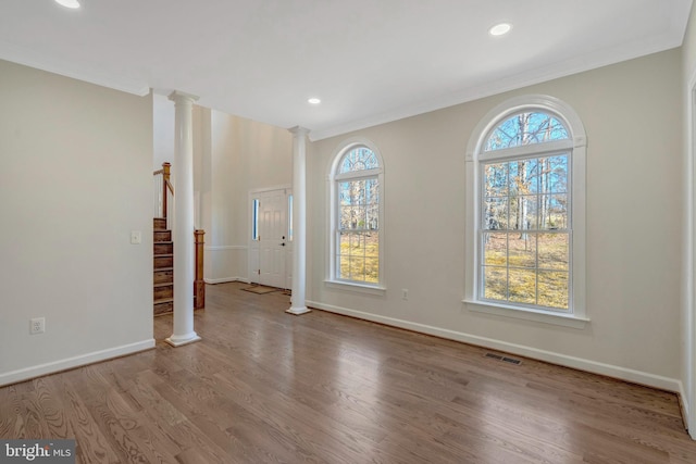 interior space featuring ornate columns, visible vents, stairway, wood finished floors, and baseboards