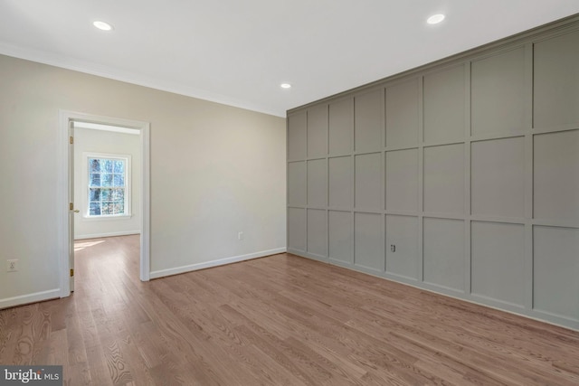 unfurnished room featuring baseboards, light wood-style flooring, ornamental molding, a decorative wall, and recessed lighting