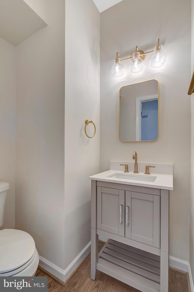 bathroom featuring vanity, wood finished floors, toilet, and baseboards