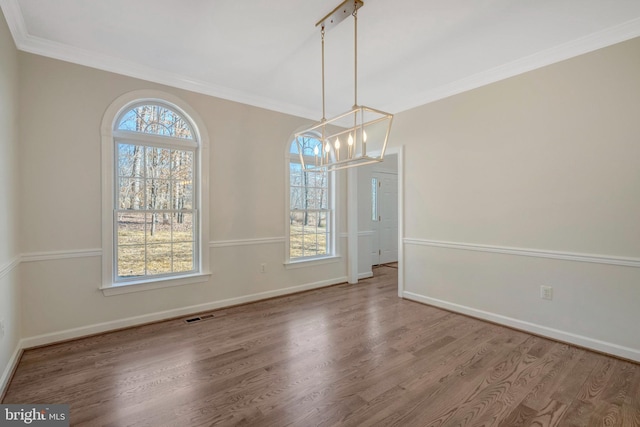 unfurnished dining area featuring baseboards, wood finished floors, visible vents, and crown molding