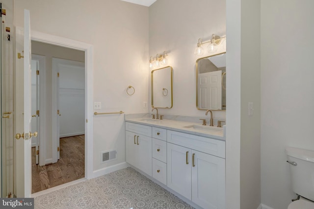 full bathroom featuring toilet, double vanity, a sink, and visible vents