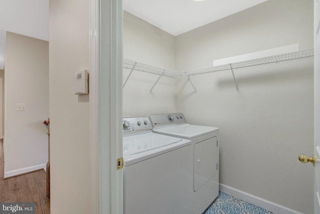 washroom with light wood-style floors, laundry area, washer and clothes dryer, and baseboards