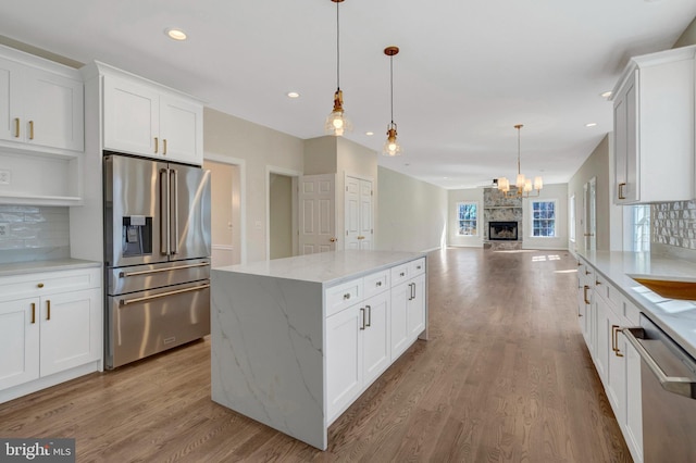 kitchen with appliances with stainless steel finishes, backsplash, wood finished floors, and a center island