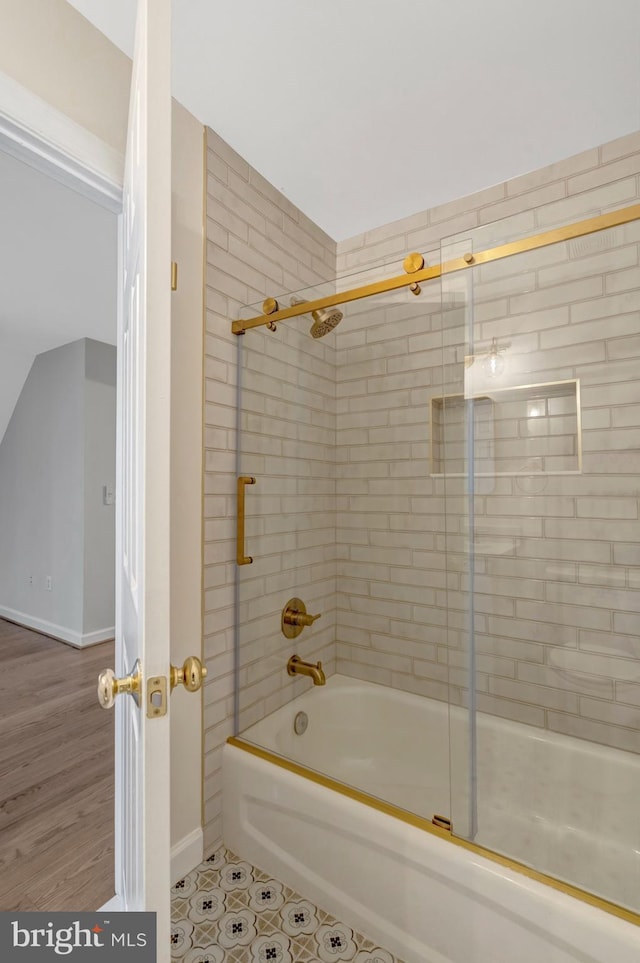 bathroom featuring combined bath / shower with glass door and baseboards