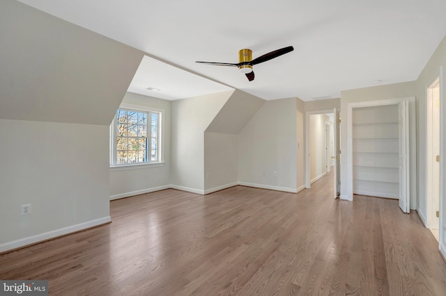 additional living space with vaulted ceiling, light wood-type flooring, a ceiling fan, and baseboards