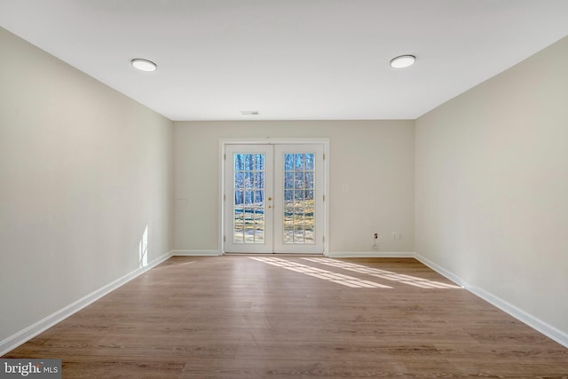 empty room with visible vents, baseboards, wood finished floors, and french doors