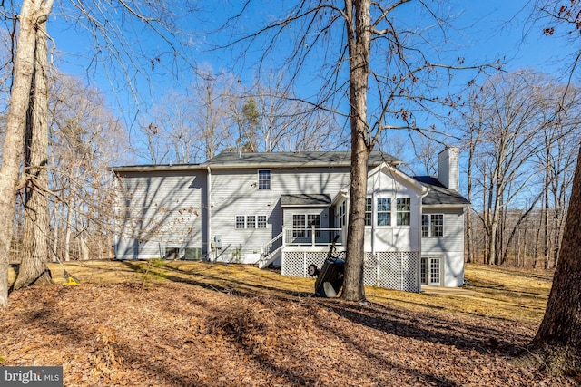 view of property exterior with a deck, a yard, and a chimney