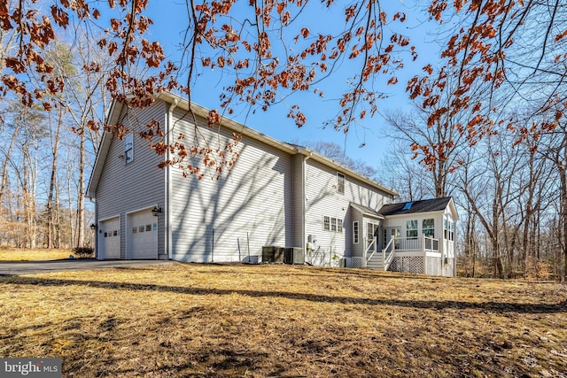 view of home's exterior featuring a garage, a yard, a porch, and driveway