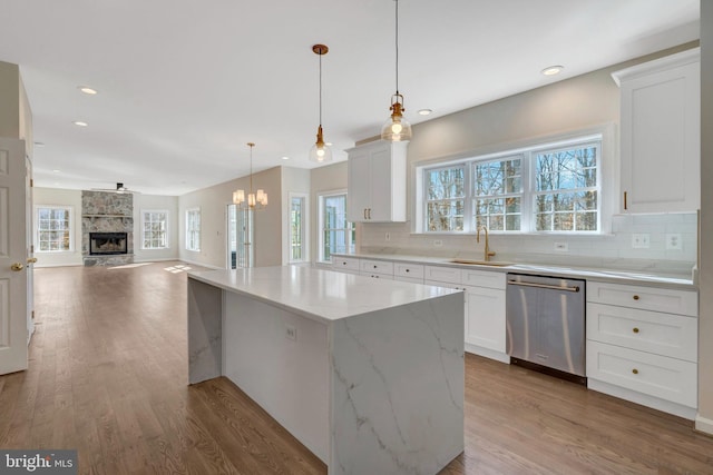 kitchen with a sink, light wood-style flooring, dishwasher, and a center island