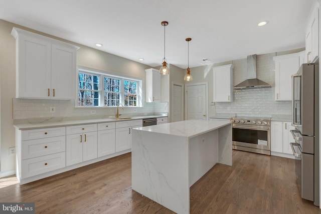 kitchen with premium appliances, a center island, a sink, wall chimney range hood, and wood finished floors