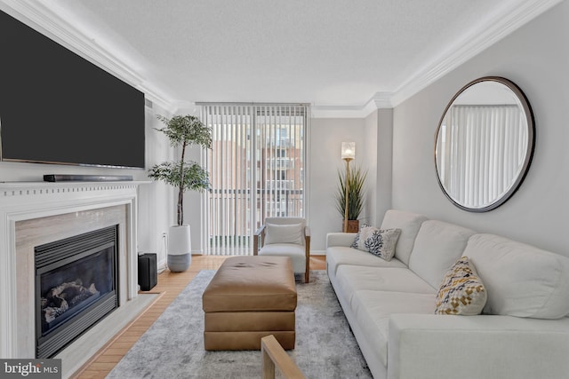 living area with a textured ceiling, ornamental molding, wood finished floors, and a high end fireplace