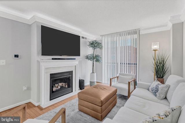 living area featuring a fireplace, visible vents, ornamental molding, wood finished floors, and baseboards