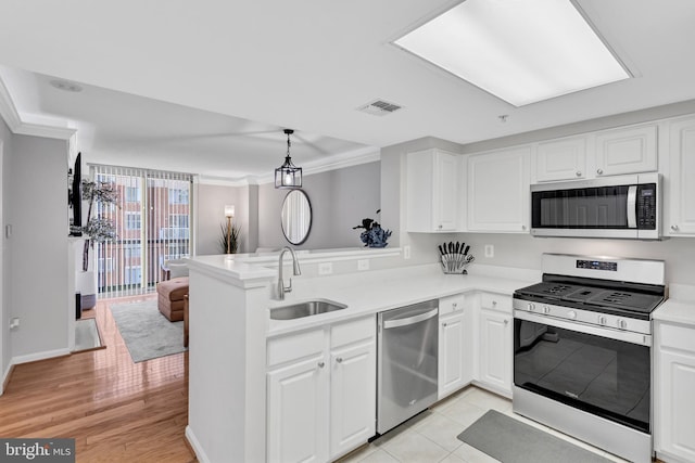 kitchen with visible vents, appliances with stainless steel finishes, white cabinets, a sink, and a peninsula