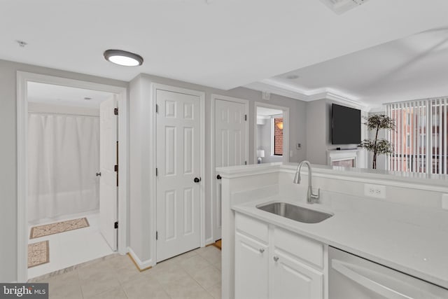 kitchen featuring light tile patterned floors, light countertops, white cabinets, a sink, and dishwasher