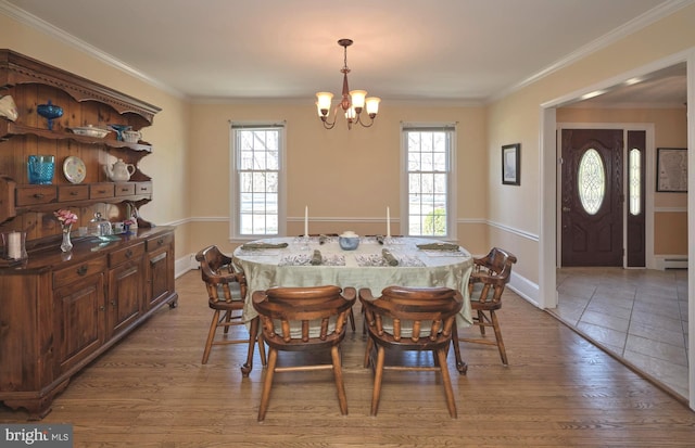 dining space featuring an inviting chandelier, plenty of natural light, light wood finished floors, and ornamental molding