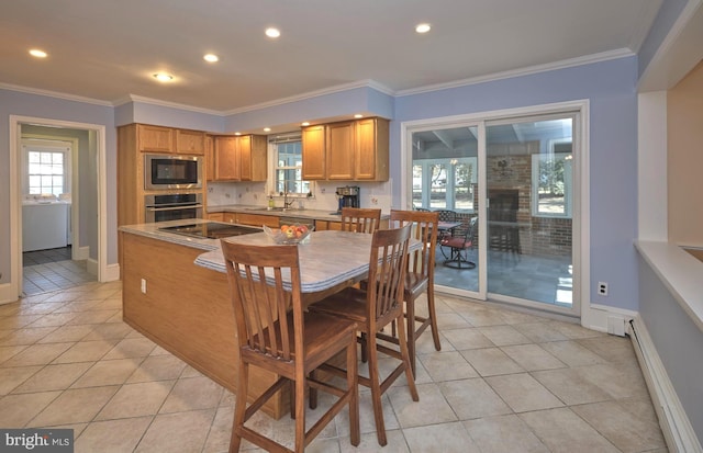 kitchen with a baseboard heating unit, ornamental molding, appliances with stainless steel finishes, light tile patterned flooring, and a sink