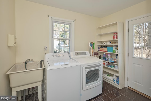 laundry area with a sink, laundry area, dark tile patterned flooring, and washing machine and clothes dryer