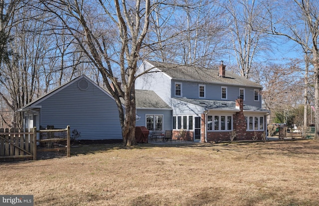 back of property with brick siding, fence, a lawn, a chimney, and a patio area