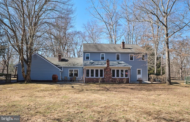 back of property featuring a yard, brick siding, and a chimney