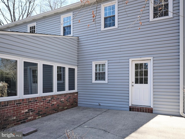 rear view of property featuring a patio and brick siding