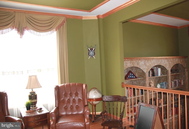 living area with wood finished floors, baseboards, and ornamental molding